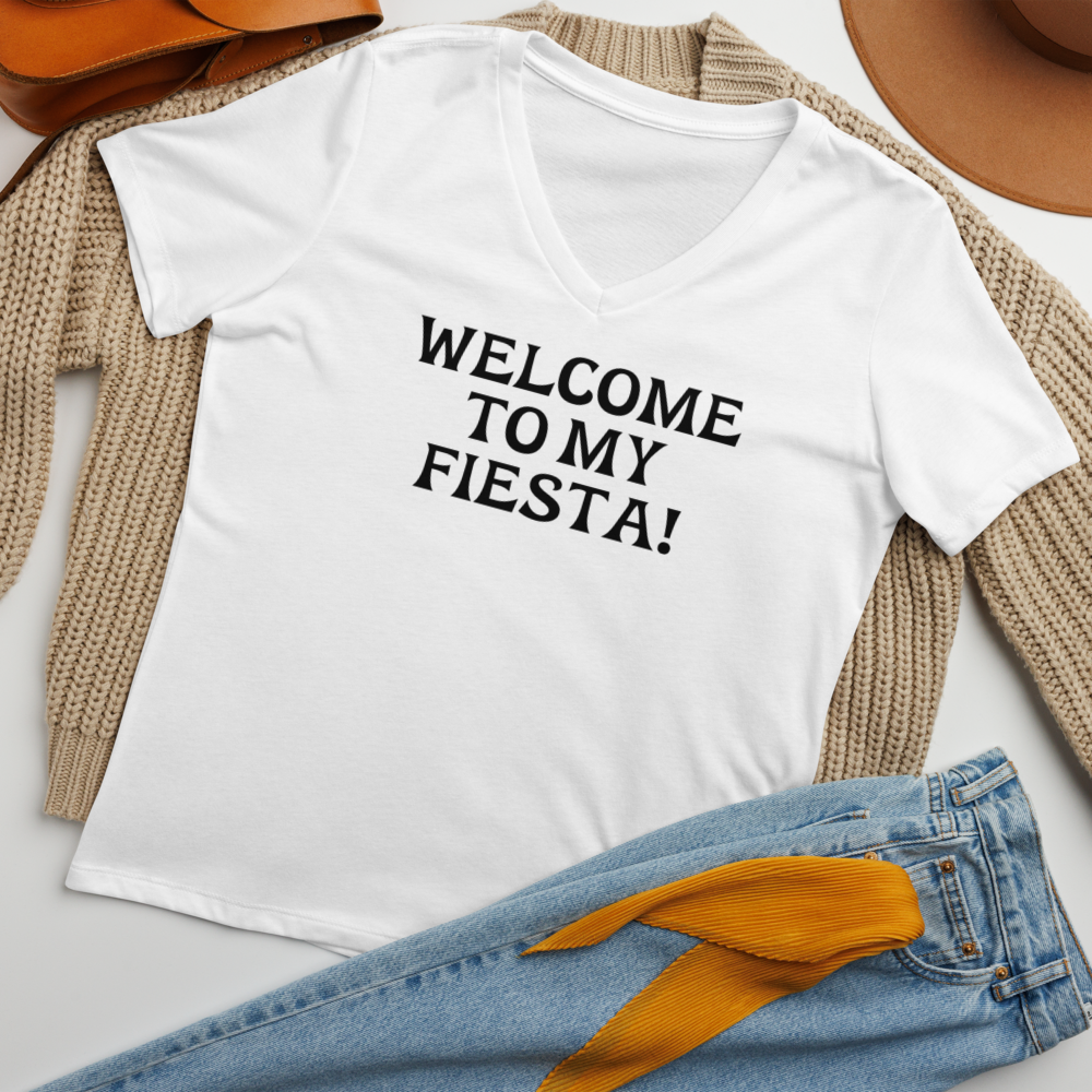 "Welcome to my fiesta!" printed on a solid white blend women's relaxed v-neck t-shirt laying on a flat surface amongst other clothes