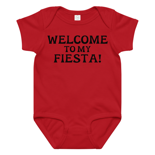 "Welcome to my fiesta!" printed on a red baby jersey bodysuit laying on a flat surface amongst other clothes