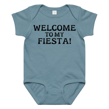"Welcome to my fiesta!" printed on a vintage indigo baby jersey bodysuit laying on a flat surface amongst other clothes