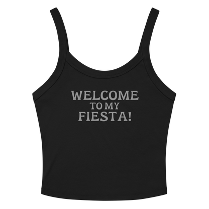 "Welcome to my fiesta!" printed on a solid black blend women's micro-rib tanktop laying on a flat surface amongst sunglasses and shorts