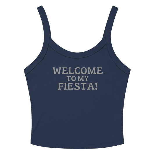 "Welcome to my fiesta!" printed on a solid navy blend women's micro-rib tanktop laying on a flat surface amongst sunglasses and shorts