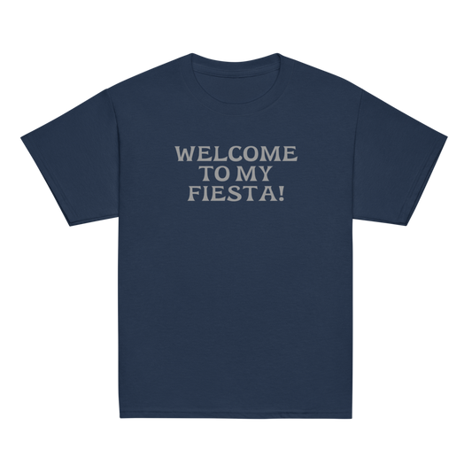 "Welcome to my fiesta!" printed on a navy youth classic tee laying on a flat surface