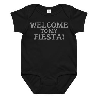 "Welcome to my fiesta!" printed on a black baby jersey bodysuit laying on a flat surface amongst other clothes
