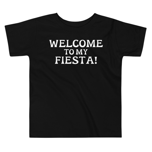 "Welcome to my fiesta!" printed on a black toddler short sleeve tee laying on a flat surface