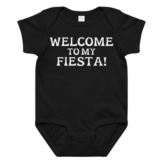 "Welcome to my fiesta!" printed on a black baby jersey bodysuit laying on a flat surface amongst other clothes
