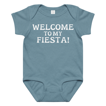 "Welcome to my fiesta!" printed on a vintage indigo baby jersey bodysuit laying on a flat surface amongst other clothes