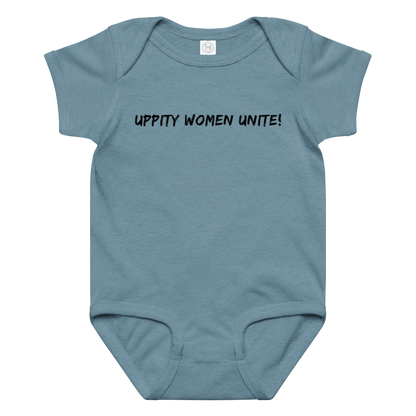 "Uppity Women Unite" printed on a vintage indigo baby jersey bodysuit laying on a flat surface amongst other clothes
