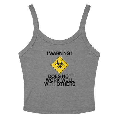 "!Warning! Does Not Work Well With Others" printed on a athletic heather women's micro-rib tanktop laying on a flat surface amongst sunglasses and shorts