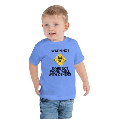 "!Warning! Does Not Work Well With Others" printed on a heather columbia blue toddler short sleeve tee worn by a male