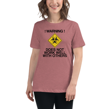"!Warning! Does Not Work Well With Others" printed on a heather mauve women's relaxed t-shirt worn by a female