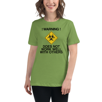 "!Warning! Does Not Work Well With Others" printed on a leaf women's relaxed t-shirt worn by a female