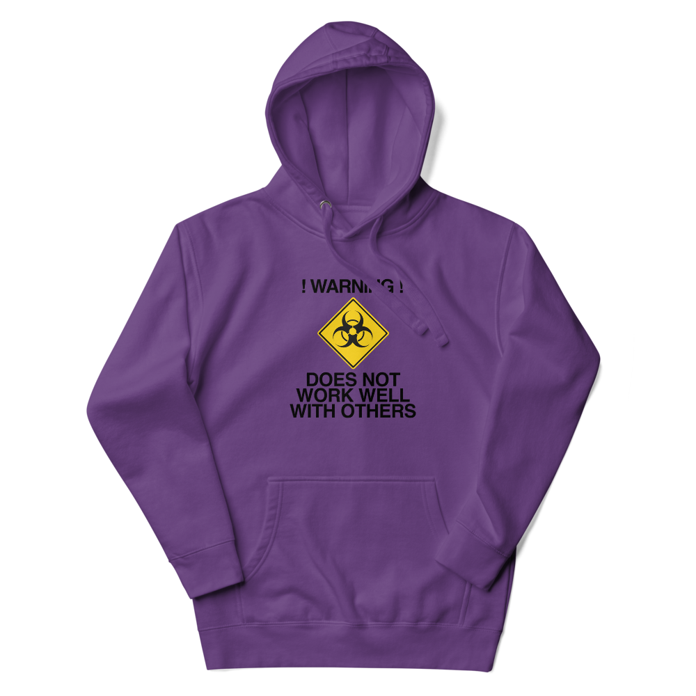 "!Warning! Does Not Work Well With Others" printed on a purple unisex hoodie laying on a flat surface with the hood up
