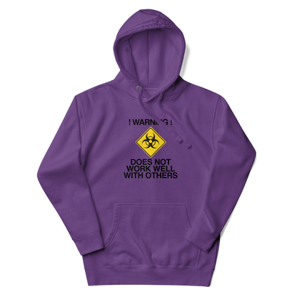 "!Warning! Does Not Work Well With Others" printed on a purple unisex hoodie laying on a flat surface with the hood up