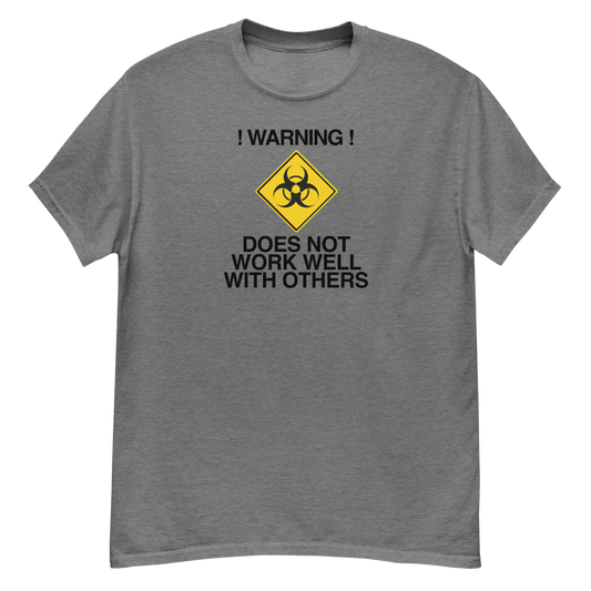 "!Warning! Does Not Work Well With Others" printed on a graphite heather unisex classic tee laying on a flat surface