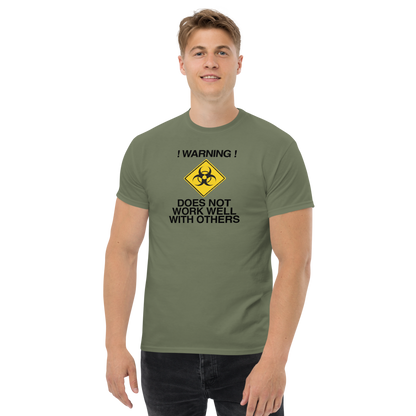 "!Warning! Does Not Work Well With Others" printed on a military green unisex classic tee worn by a male