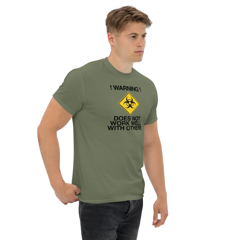 "!Warning! Does Not Work Well With Others" printed on a military green unisex classic tee worn by a male