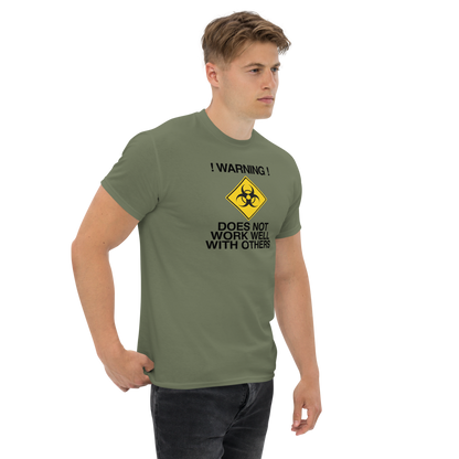 "!Warning! Does Not Work Well With Others" printed on a military green unisex classic tee worn by a male