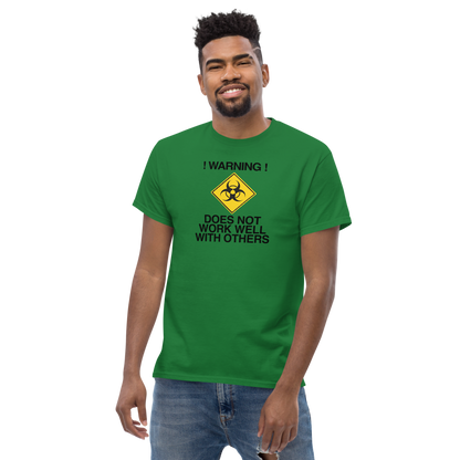 "!Warning! Does Not Work Well With Others" printed on a turf green unisex classic tee worn by a male