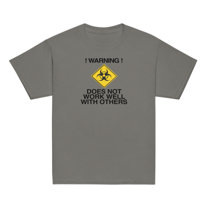 "!Warning! Does Not Work Well With Others" printed on a charcoal youth classic tee laying on a flat surface