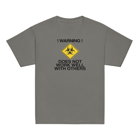 "!Warning! Does Not Work Well With Others" printed on a charcoal youth classic tee laying on a flat surface