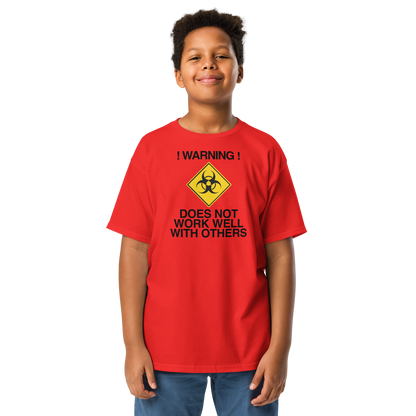 "!Warning! Does Not Work Well With Others" printed on a red youth classic tee worn by a male