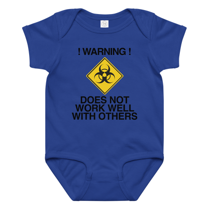 "!Warning! Does Not Work Well With Others" printed on a royal baby jersey bodysuit laying on a flat surface amongst other clothes