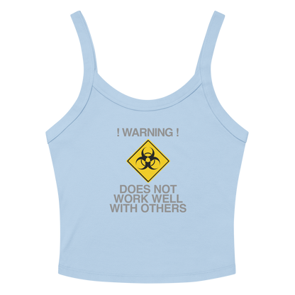 "!Warning! Does Not Work Well With Others" printed on a solid baby blue blend women's micro-rib tanktop laying on a flat surface amongst sunglasses and shorts