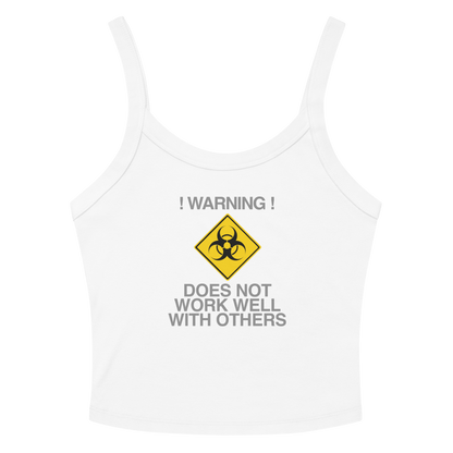 "!Warning! Does Not Work Well With Others" printed on a solid white blend women's micro-rib tanktop laying on a flat surface amongst sunglasses and shorts