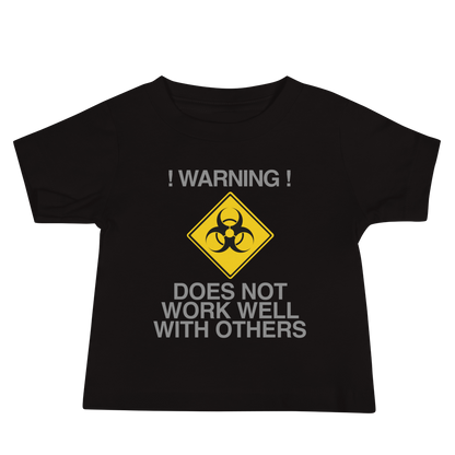 "!Warning! Does Not Work Well With Others" printed on a black baby jersey short sleeve tee laying on a flat surface