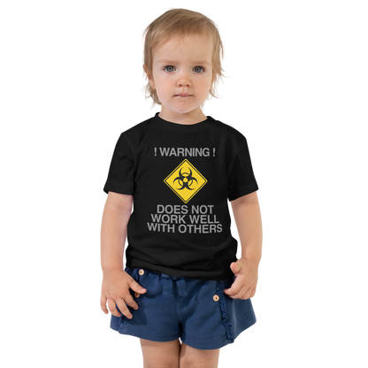 "!Warning! Does Not Work Well With Others" printed on a black toddler short sleeve tee worn by a female