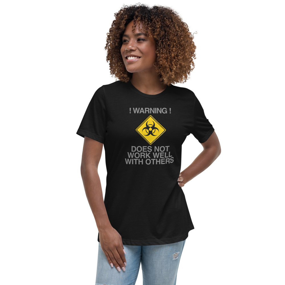 "!Warning! Does Not Work Well With Others" printed on a black women's relaxed t-shirt worn by a female