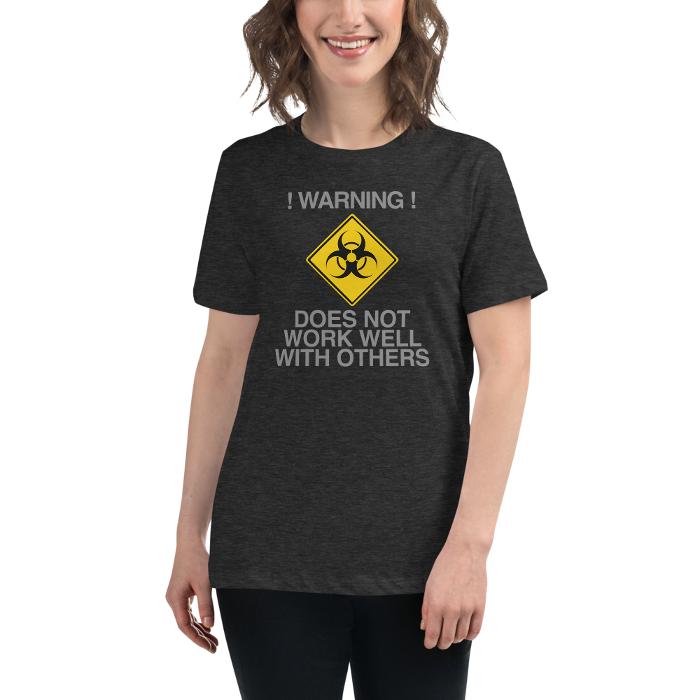 "!Warning! Does Not Work Well With Others" printed on a dark grey heather women's relaxed t-shirt worn by a female