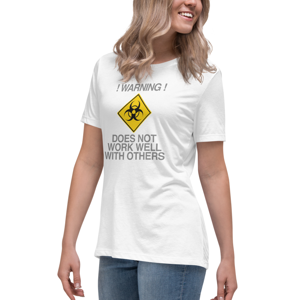 "!Warning! Does Not Work Well With Others" printed on a white women's relaxed t-shirt worn by a female
