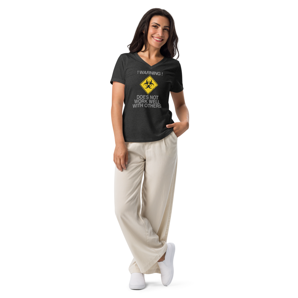 "!Warning! Does Not Work Well With Others" printed on a dark grey heather women's relaxed v-neck t-shirt worn by a female