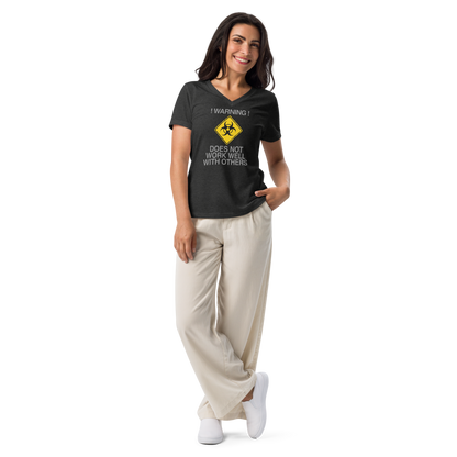"!Warning! Does Not Work Well With Others" printed on a dark grey heather women's relaxed v-neck t-shirt worn by a female