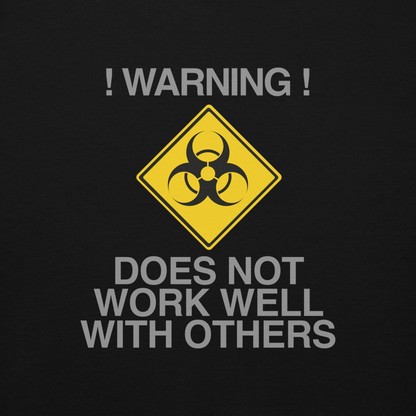 "!Warning! Does Not Work Well With Others" printed on a black background