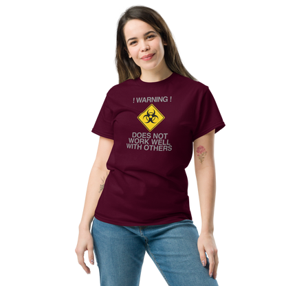 "!Warning! Does Not Work Well With Others" printed on a maroon unisex classic tee worn by a female