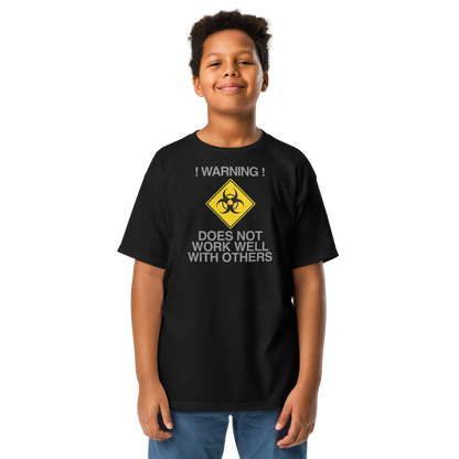 "!Warning! Does Not Work Well With Others" printed on a black youth classic tee worn by a male