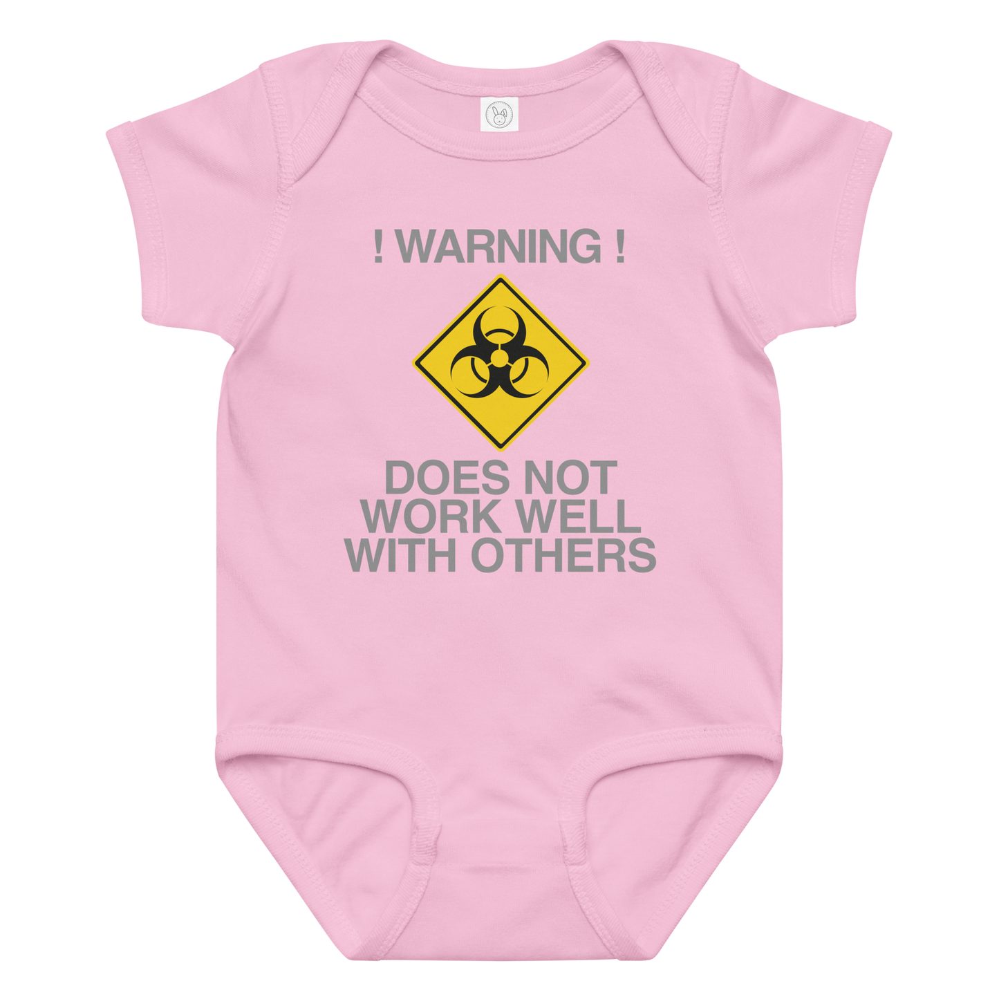 "!Warning! Does Not Work Well With Others" printed on a pink baby jersey bodysuit laying on a flat surface amongst other clothes