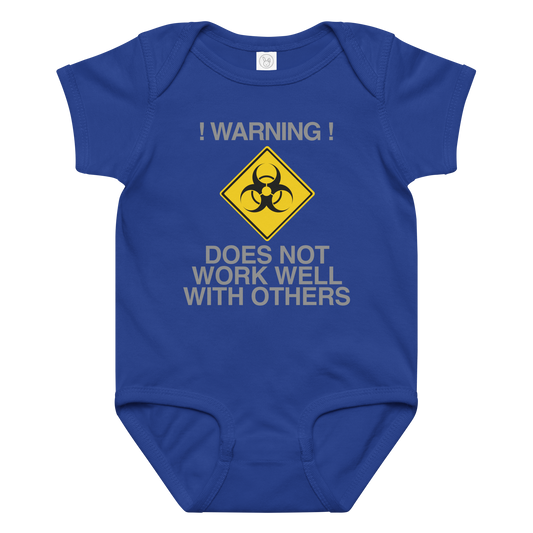 "!Warning! Does Not Work Well With Others" printed on a royal baby jersey bodysuit laying on a flat surface amongst other clothes