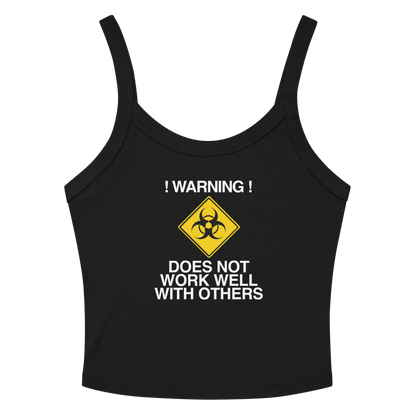 "!Warning! Does Not Work Well With Others" printed on a solid black blend women's micro-rib tanktop laying on a flat surface amongst sunglasses and shorts