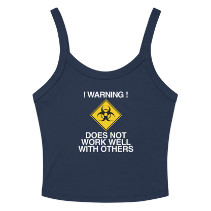 "!Warning! Does Not Work Well With Others" printed on a solid navy blend women's micro-rib tanktop laying on a flat surface amongst sunglasses and shorts