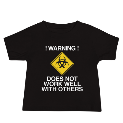 "!Warning! Does Not Work Well With Others" printed on a black baby jersey short sleeve tee laying on a flat surface