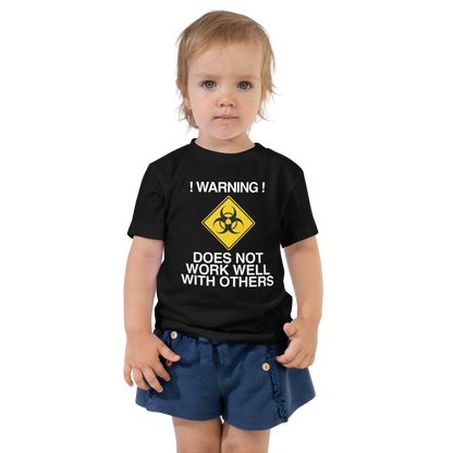 "!Warning! Does Not Work Well With Others" printed on a black toddler short sleeve tee worn by a female