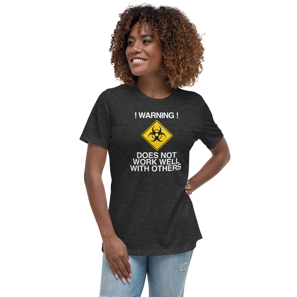 "!Warning! Does Not Work Well With Others" printed on a dark grey heather women's relaxed t-shirt worn by a female