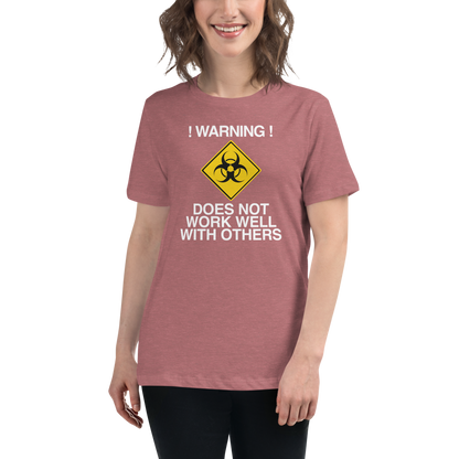"!Warning! Does Not Work Well With Others" printed on a heather mauve women's relaxed t-shirt worn by a female