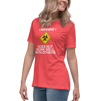 "!Warning! Does Not Work Well With Others" printed on a heather red women's relaxed t-shirt worn by a female