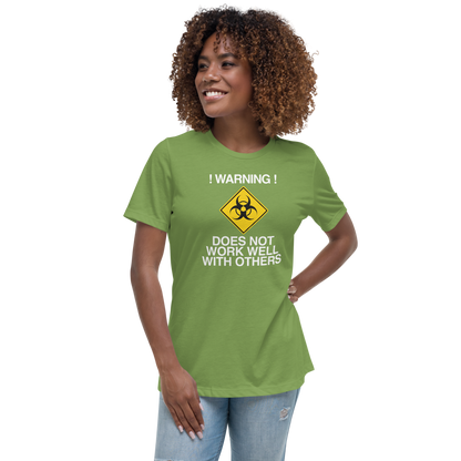 "!Warning! Does Not Work Well With Others" printed on a leaf women's relaxed t-shirt worn by a female