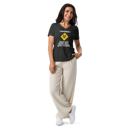 "!Warning! Does Not Work Well With Others" printed on a dark grey heather women's relaxed v-neck t-shirt worn by a female