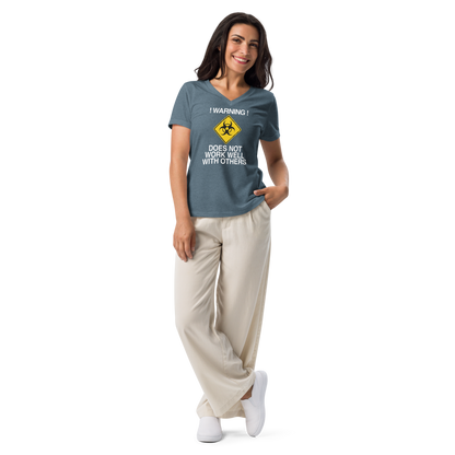 "!Warning! Does Not Work Well With Others" printed on a heather slate women's relaxed v-neck t-shirt worn by a female